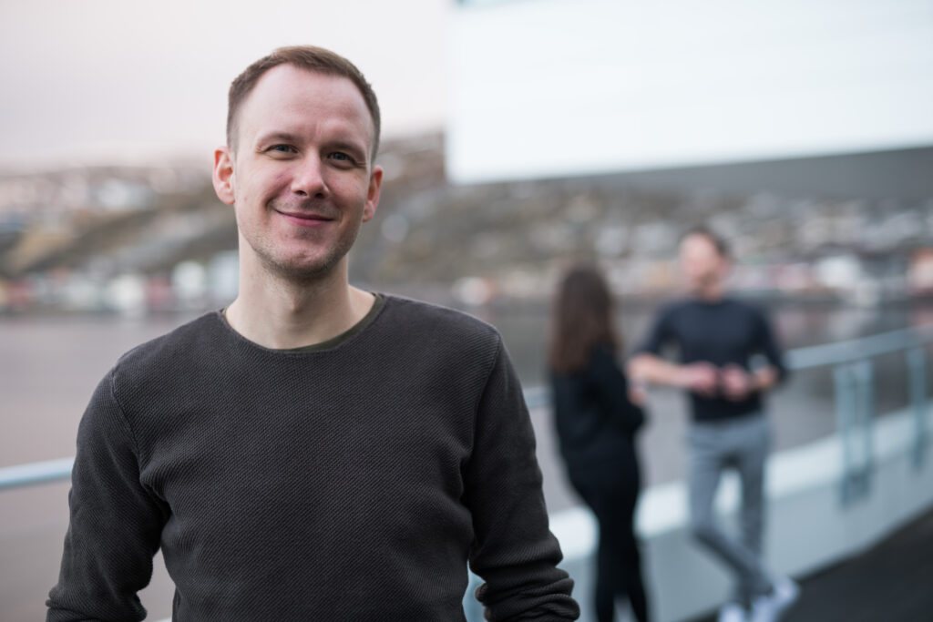 Ansatt står utendørs og smiler til kamera. Foto