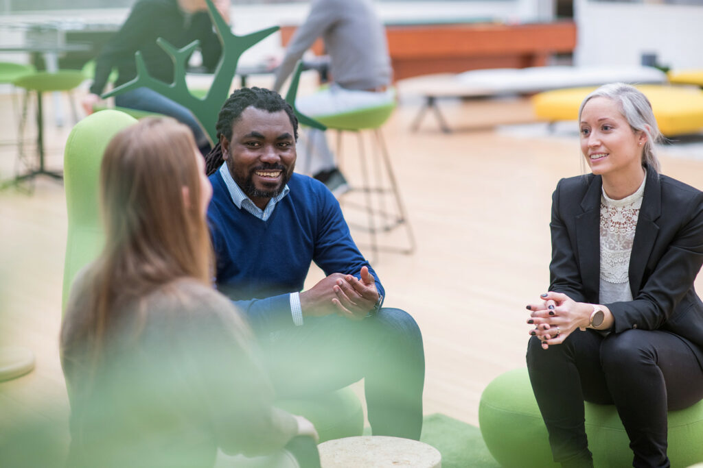 Tre ansatte sitter sammen og snakker